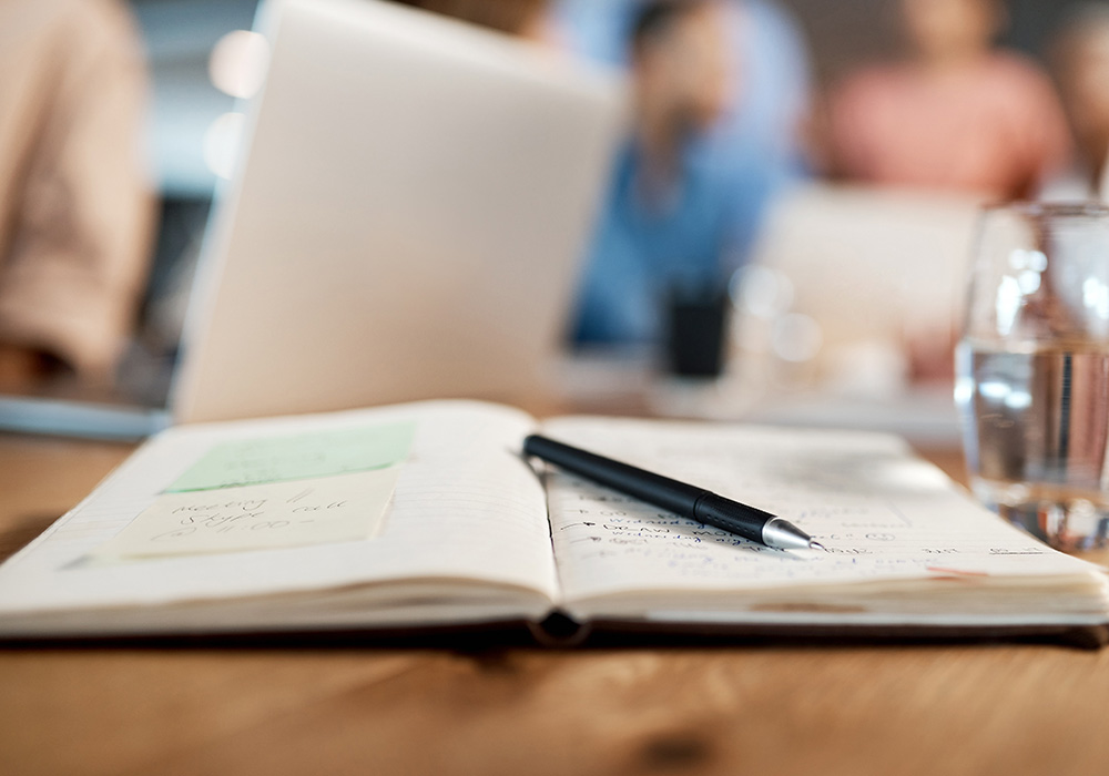 open notebook on a table with a pen lying on it at the ICC 10K Lakes September 2023 Meeting