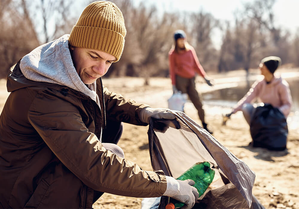 chapter members wearing gloves and chatting pick up trash from around the shore of a lake at the ICC 10K Lakes Roadside Cleanup